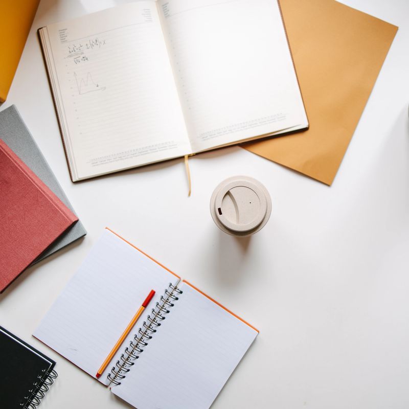 Top view of a desk with open notebook, coffee cup, pen and sticky notes