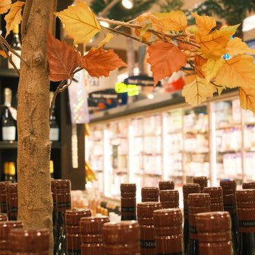 Wine bottles displayed near autumn-themed decor in a store.