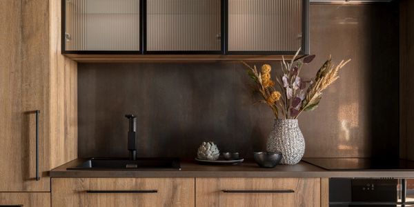Modern kitchen countertop with wooden cabinets and decorative dried flowers.