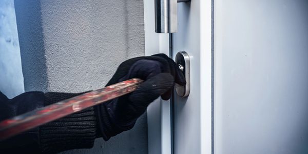 Einbrecher versucht eine Haustür zu öffnen.