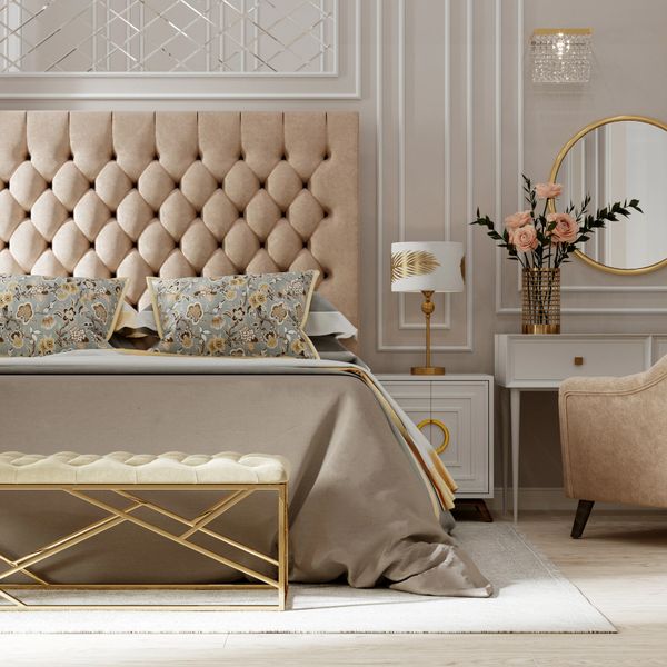 Luxurious beige bedroom with tufted headboard, floral pillows, and gold accents.