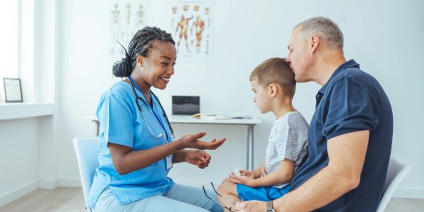Doctor talking to a child and parent during medical consultation.