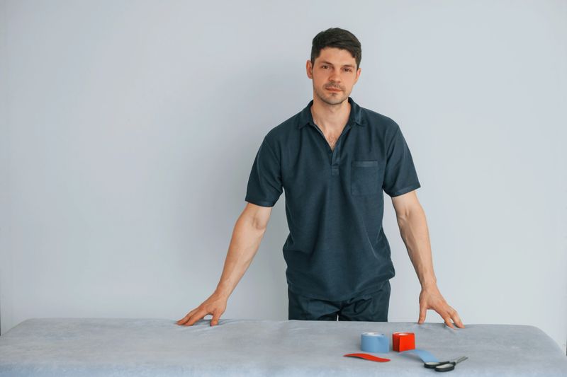 Professional physiotherapist is standing indoors with kinesio tape.