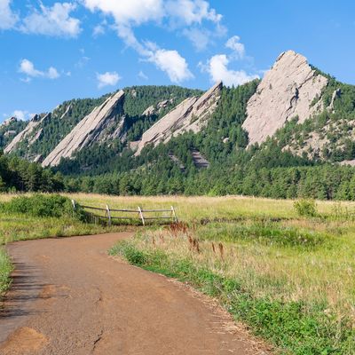 Winding dirt path leading to rugged rock formations under a blue sky.