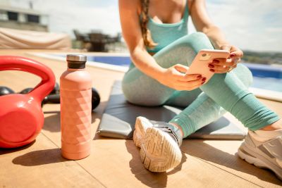 Woman in workout clothes using phone after exercising.