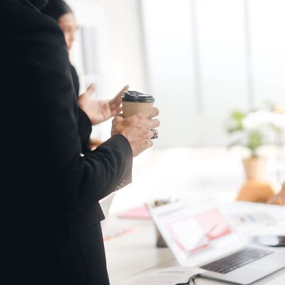 Person holding a coffee cup during a business discussion.