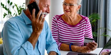Elderly couple using a laptop and phone for online shopping.