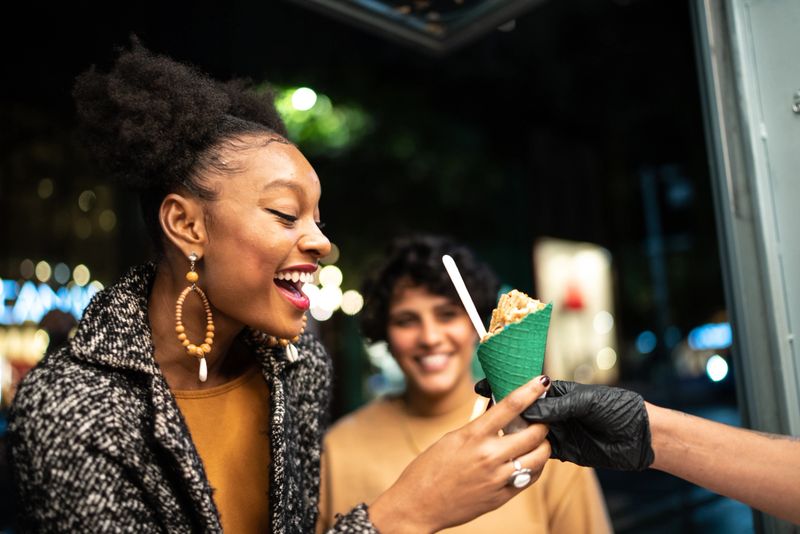 Young woman buying ice cream in the street at night