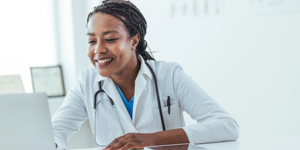 Smiling female doctor using laptop in a bright office.