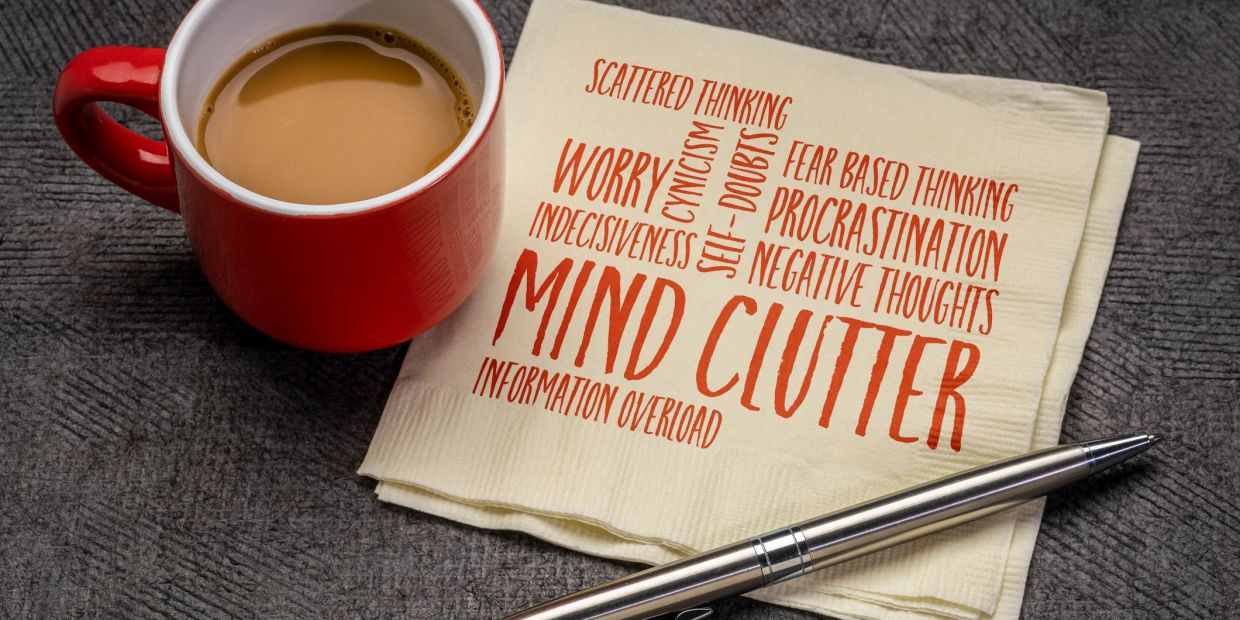 Red cup of coffee with napkin reading "Mind Clutter" and related words.