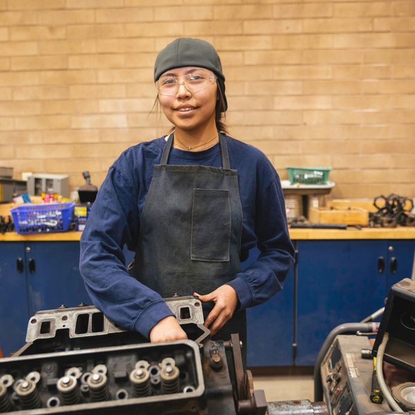 Young woman mechanic working on an engine in a workshop.