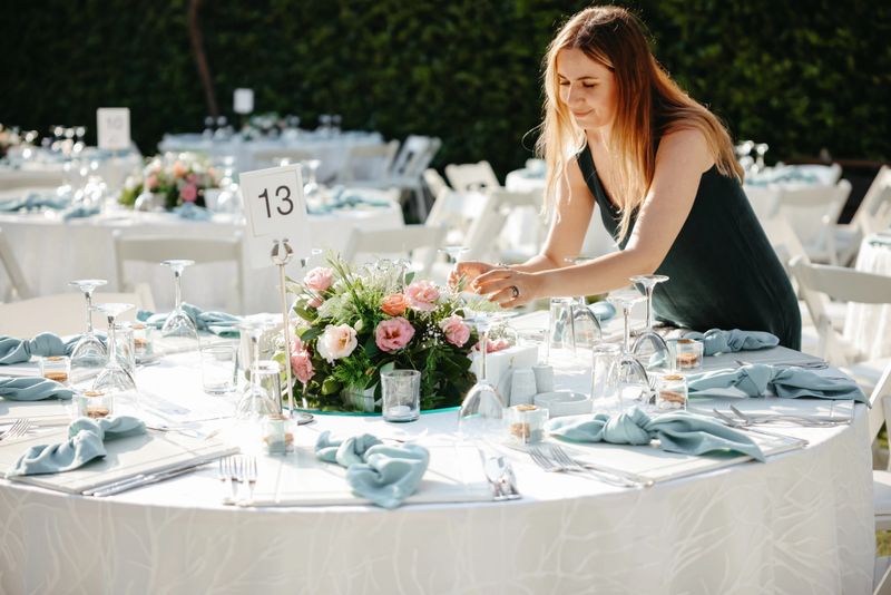 Shot of a young woman decorating a table with place card holders in preparation for a wedding reception