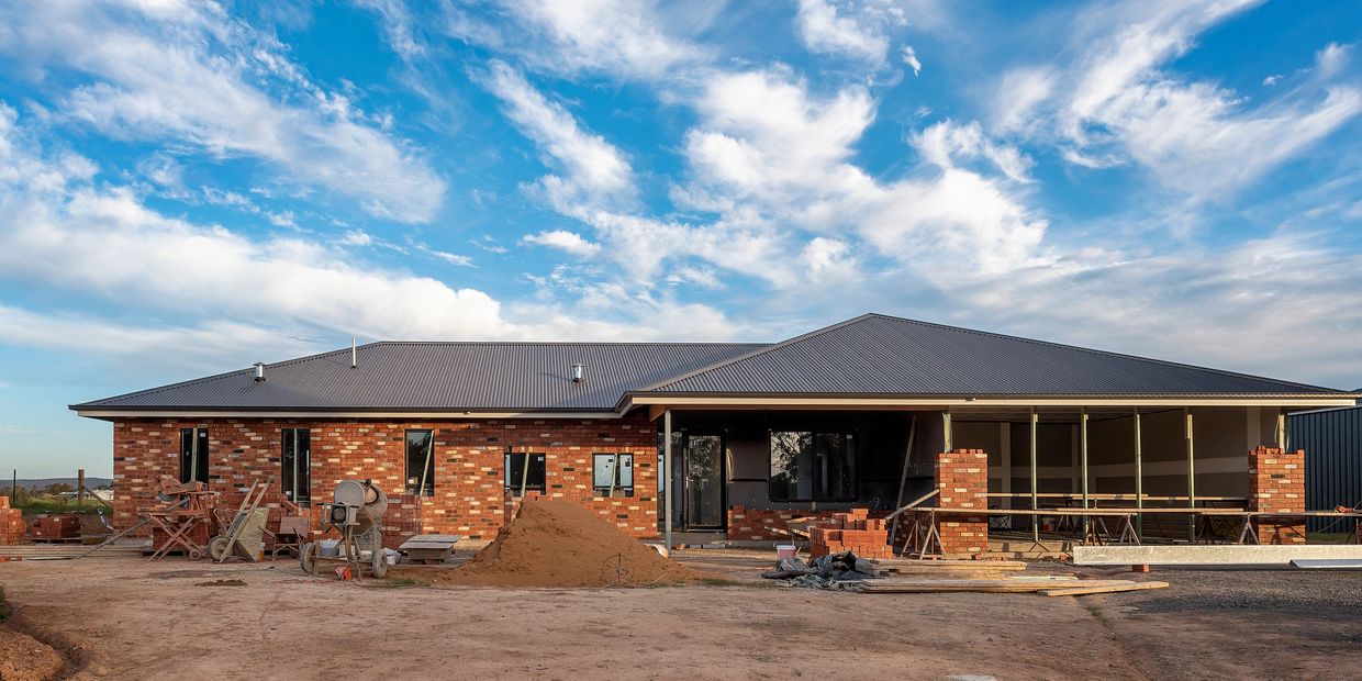 A house under construction with wooden framework and cinder blocks in a residential neighborhood.