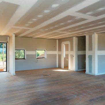 Spacious unfinished room with large windows and wooden flooring under construction.