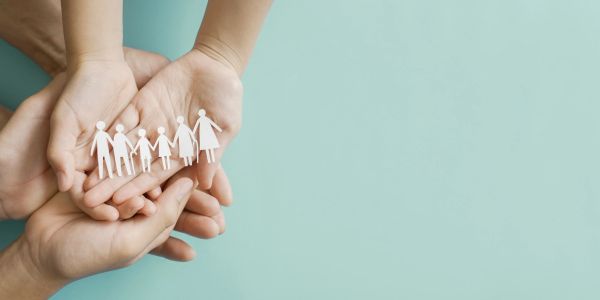 Hands holding paper cutout family figures.