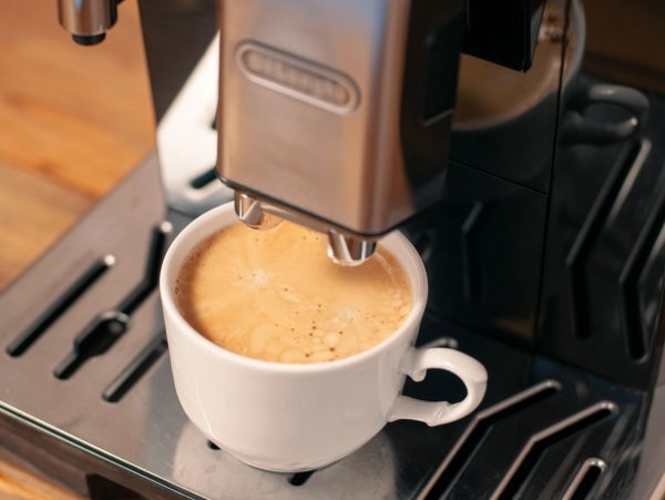 Espresso pouring into a white cup from a coffee machine.