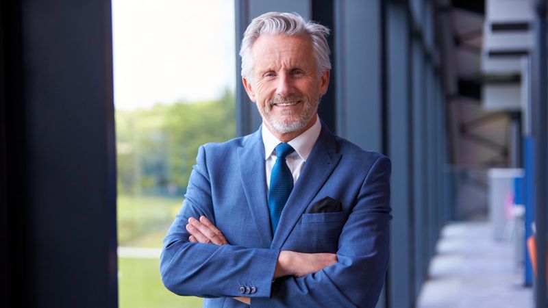 Portrait Of Smiling Senior Businessman CEO Chairman Standing Inside Modern Office Building