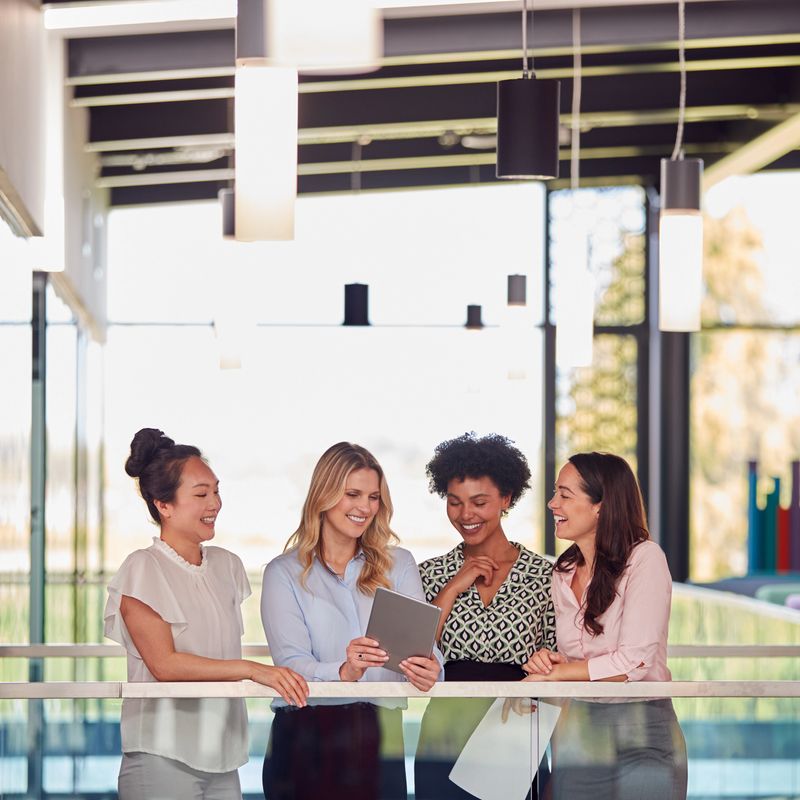 Multi-Cultural Female Business Team With Digital Tablet  Meeting Inside Modern Office Building