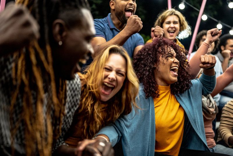 Friends watching a sports game and celebrating outdoors