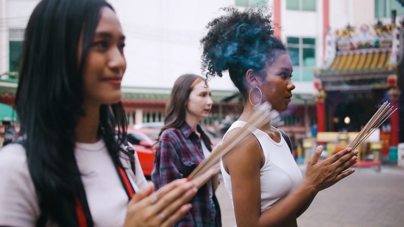 A group of multi-ethnic female friends praying at a Chinese shrine in Bangkok, Thailand.