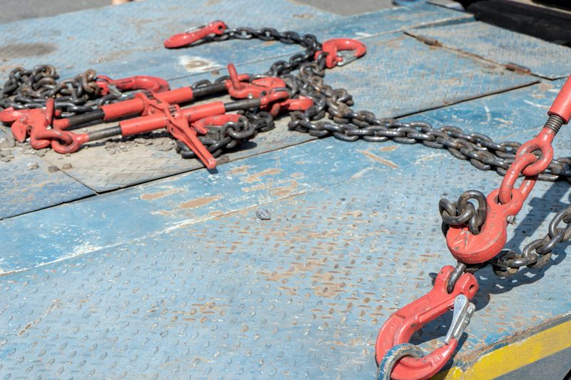 Crane hook, on which chains with hooks and fastening elements are attached. Lifting mechanism in production and warehouse close-up.