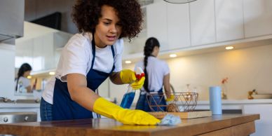 Woman cleaning a wooden table in the kitchen.