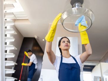 Woman cleaning a light fixture while a man mops the floor.
