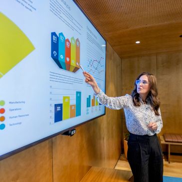 Presenter showing enrollment and demographic data on a screen — Demographic Studies & Facilities Mas