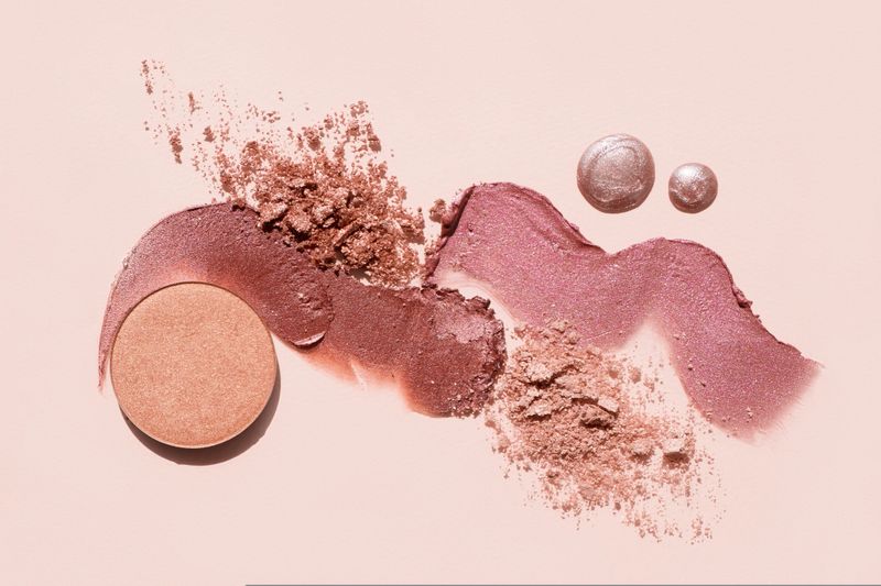 Cosmetics swatches. Peach, beige, red and coral toned styled cosmetics flat lay. Closeup colour palette. Creative concept photo of cosmetics samples. Beauty products on pastel background.