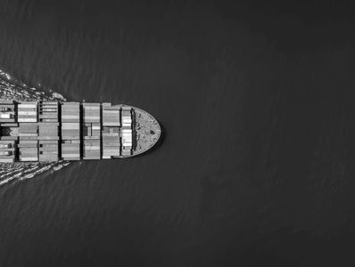 Aerial view of a container ship moving through dark water.