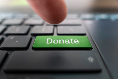 Finger pressing green Donate key on keyboard.