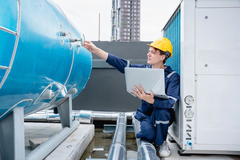 An industry engineer is inspecting the industry cooling tower air conditioner of a huge industrial structure in order to manage air flow.