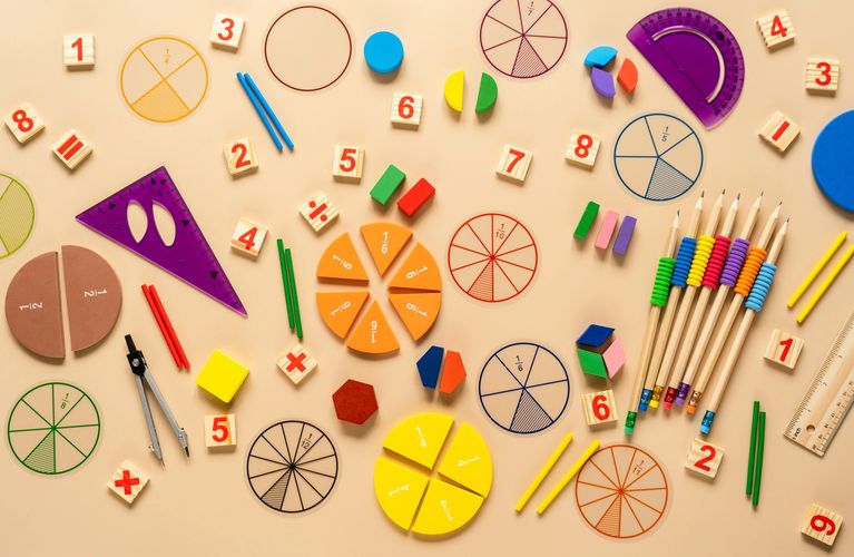 Variety  of math  resources scattered on a table such as number tiles, fraction circles, compass etc