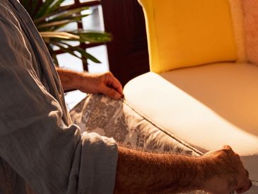 Person adjusting a cushion on a sofa.
