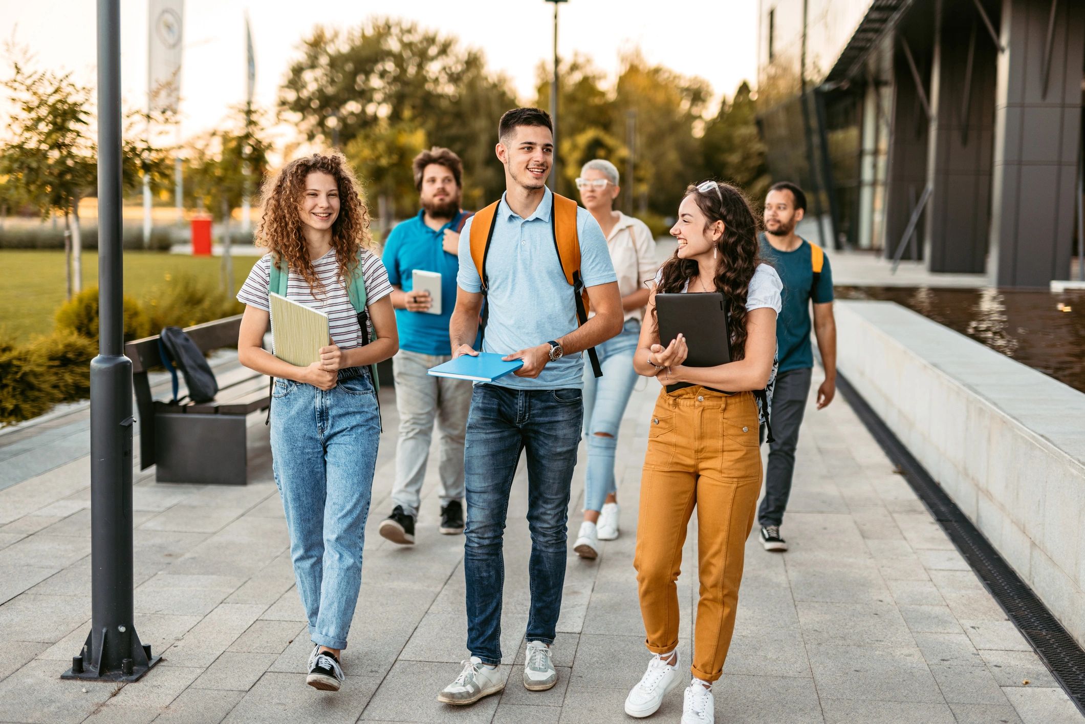 Group of happy college students walking outdoors.