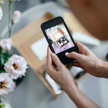 Person taking a photo of a box with a smartphone.