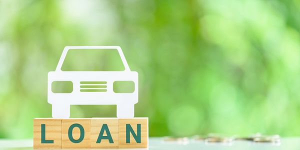 Wooden blocks spelling LOAN with a car icon on top, symbolizing a car loan.