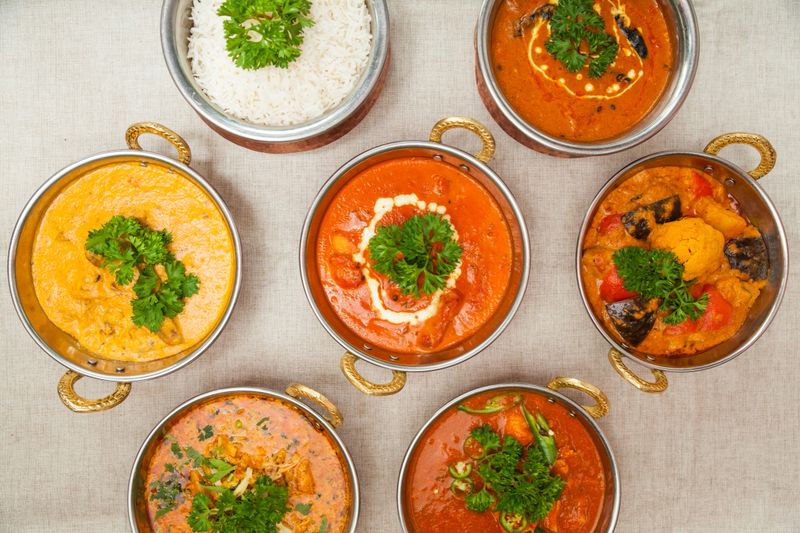 assorted indian food Plain rice, Chicken butter masala, Beef handi, Mushroom jalfrezi, Chicken korma, chicken curry, Chicken chili, Beef vindaloo served in a dish isolated on table top view