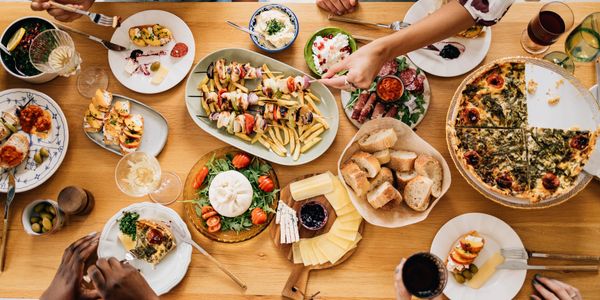 A diverse spread of Mediterranean dishes shared among friends at a wooden table.