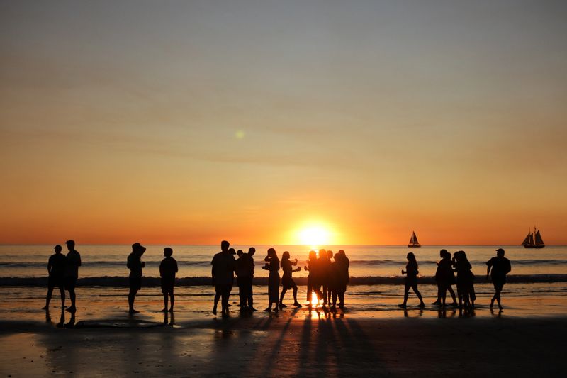 Silhouette of group of young people having a beach party during sunset.