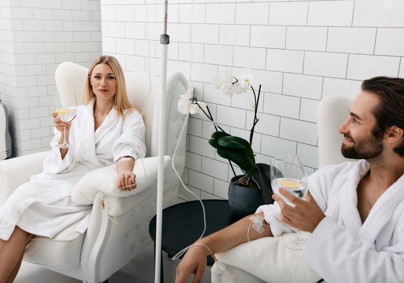 Couple in love during intravenous vitamin therapy. Beautiful woman with her boyfriend with glasses of refreshing drink with lemon in medical clinic for detox their organisms