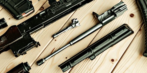 Disassembled rifle parts on a wooden surface.