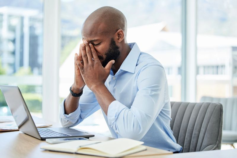Stress, anxiety and worry with a business man suffering from a headache, migraine or mental fatigue and burnout. Young male working in his office, feeling the pressure of a deadline and struggling