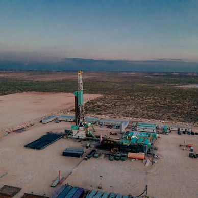 Aerial view of an oil drilling site in a remote desert area at dusk.