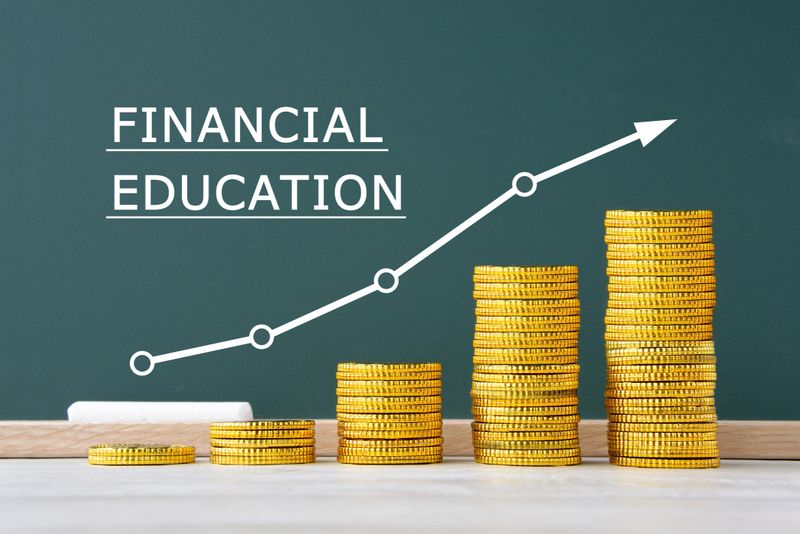Piled coins and upward arrow with "FINANCIAL EDUCATION" word on balckboard