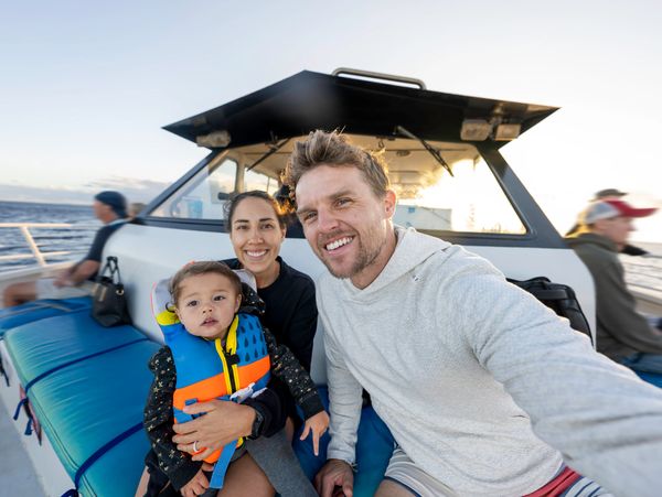 A happy family taking a selfie on a boat with ocean in the background.