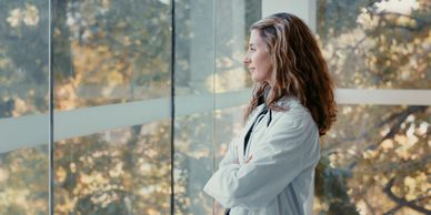 Woman in lab coat looking out a window.