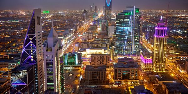 Night view of a vibrant city skyline with illuminated skyscrapers and streets.