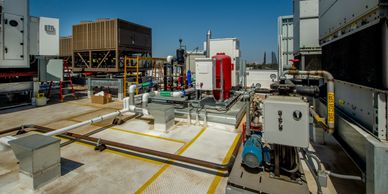 Rooftop HVAC system with pipes and machinery under clear blue sky.