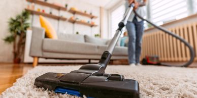 Person vacuuming a carpet in a living room.